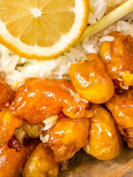 Chinese Chicken in Lemon Sauce served in a wooden bowl with chopsticks. Lemon wheel as garnish