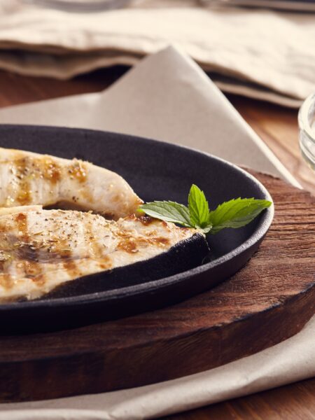 Grilled Swordfish with Oregano Sauce served on a plate; placed on a wooden board