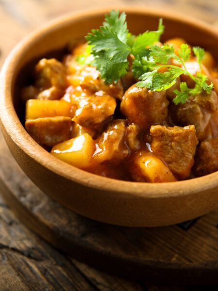 Pineapple Chicken served in a wooden bowl with garnish