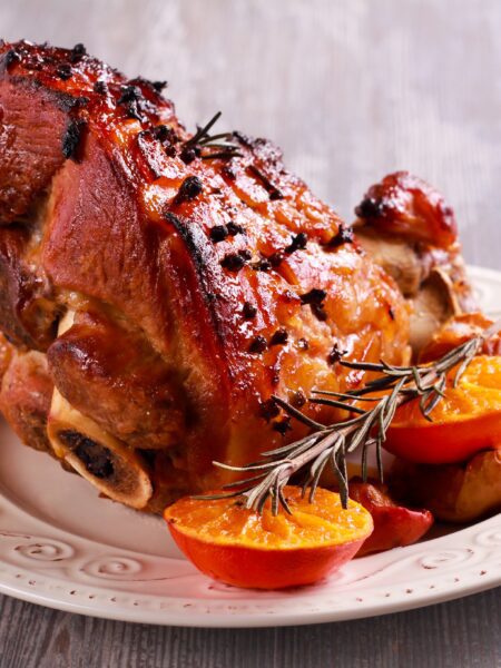 Spicy Orange Gammon Bake served on a white plate; garnished with baked oranges